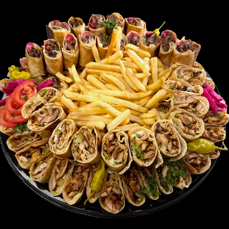 Large platter of assorted chicken shawarma wraps, sliced meat wraps, French fries, pickles, tomatoes, and pickled vegetables.